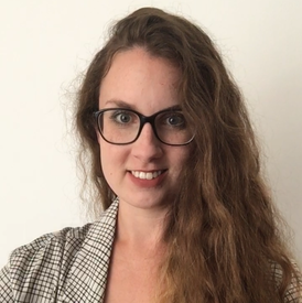 A dark blonde woman with long, curly hair and glasses